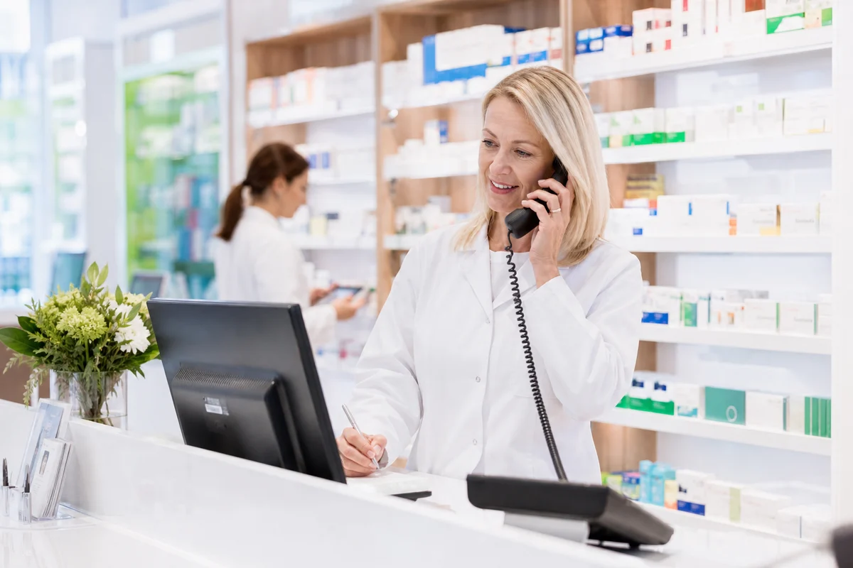 A pharmacist answers a customer call behind the consultation counter